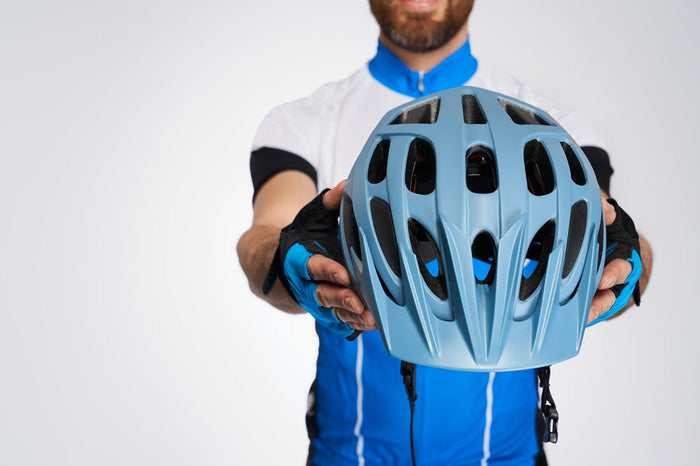 A cyclist holding a bicycle helmet in his hands