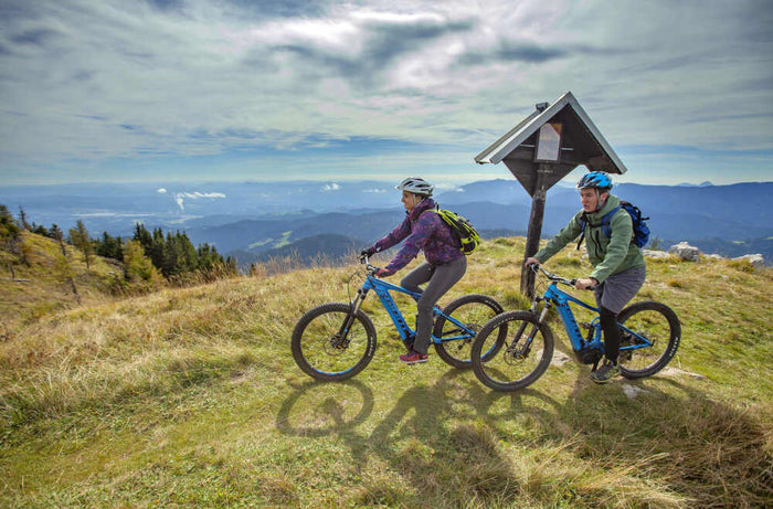 A young cycling couple travels through the mountains