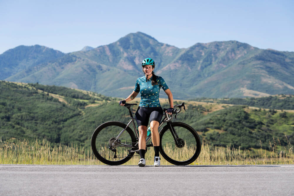 A cyclist taking a break on the road with mountains in the background