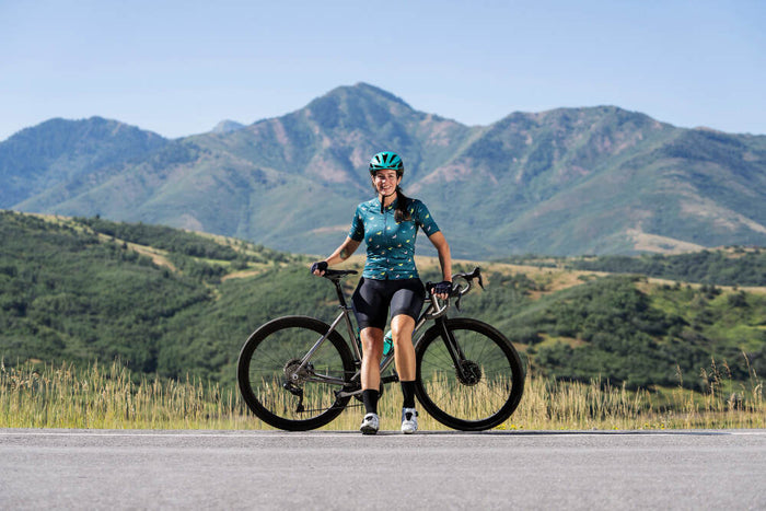 A cyclist taking a break on the road with mountains in the background