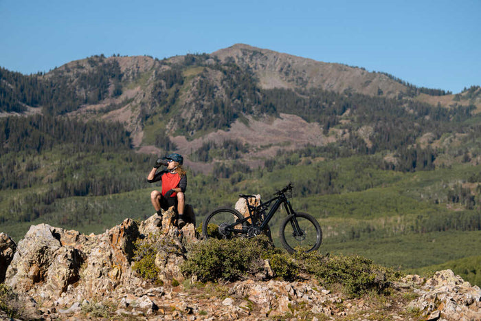 Cyclist taking a break during a mountain ride, with scenic peaks in the background